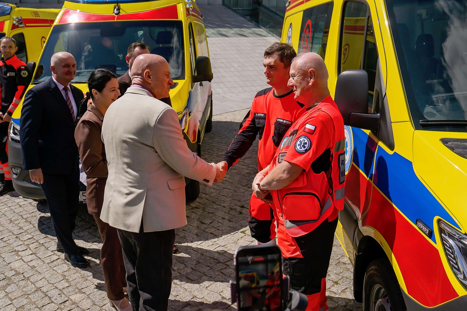 Uścisk dłoni przedstawiciela władz z ratownikiem medycznym przy nowym ambulansie