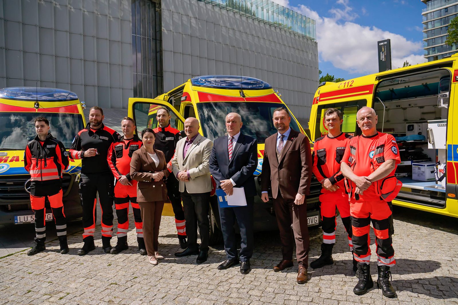 Wspólne zdjęcie uczestników uroczystości przed trzema nowymi ambulansami
