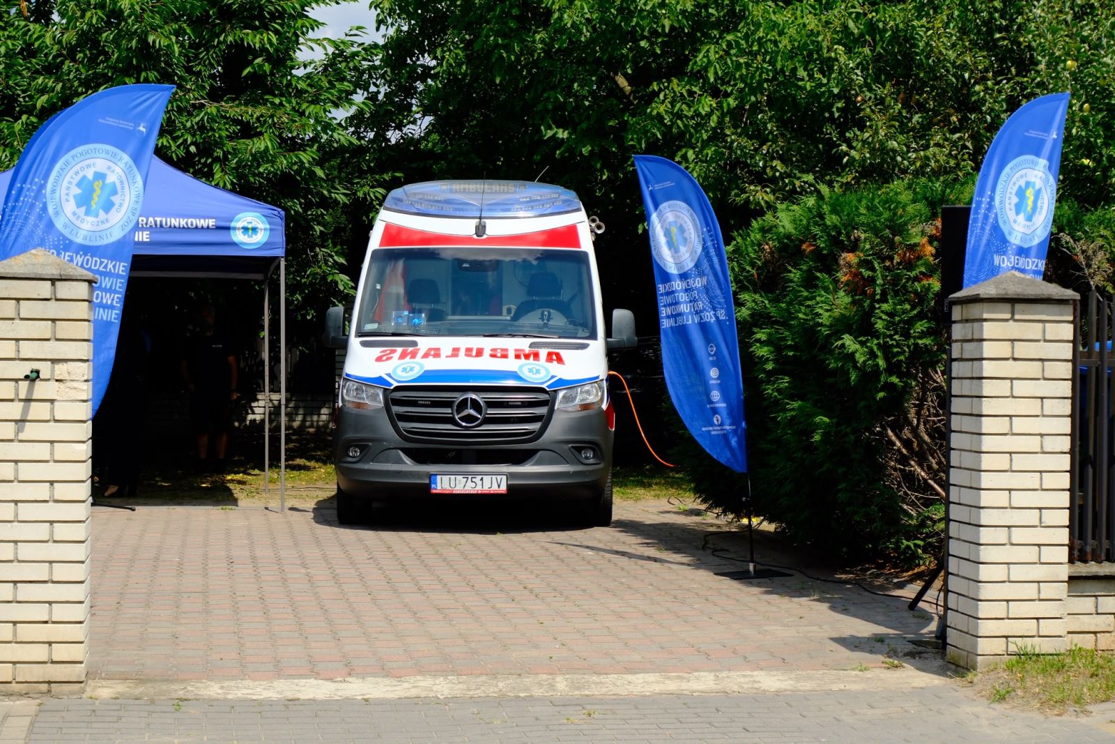 Ambulans wjeżdżający na teren punktu wyjazdowego, po bokach banery pogotowia