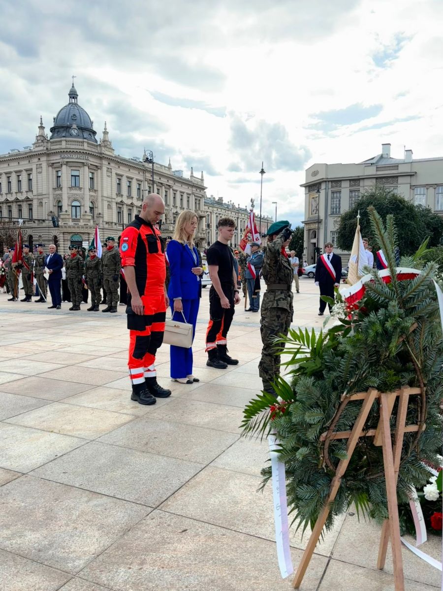 Ratownicy medyczni w mundurach pogotowia obok wieńców złożonych podczas uroczystości
